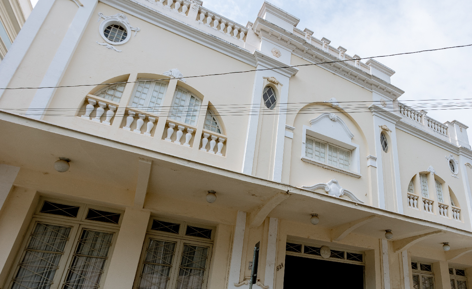 Fotografia colorida da fachada do Teatro São José. As paredes são em amarelo claro, com alguns frisos brancos. No segundo andar, há duas grandes janelas que formam um semicírculo com a base reta virada para baixo. Entre elas, há uma janela retangular. No andar térreo, estão uma porta principal ao centro e quatro secundárias, duas de cada lado.